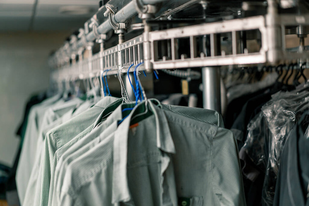 Oteldeki endüstriyel çamaşırhaneler, çamaşır iplerine tutunduktan sonra temizlenmiş işçi ve konukseverlik gömlekleri. - Fotoğraf, Görsel