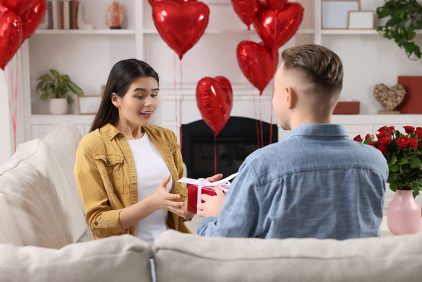 Woman receiving gift box from her boyfriend at home. Valentine's day celebration. - 写真・画像
