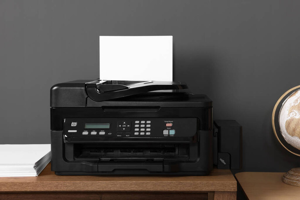 Modern printer with paper on wooden desk at home - Fotó, kép