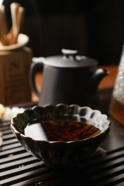 Cup with freshly brewed pu-erh tea on wooden tray, closeup - Foto, afbeelding