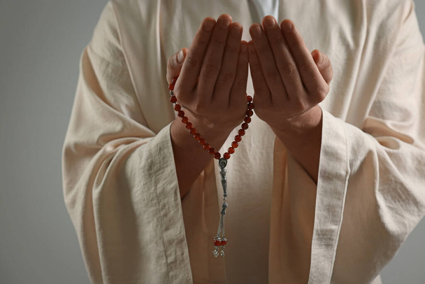 Muslimischer Mann mit Misbaha-Gebet auf hellgrauem Hintergrund, Nahaufnahme - Foto, Bild