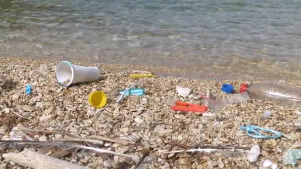 閉鎖:アドリア海によって洗浄されたプラスチック廃棄物によって汚染されたペブルビーチ。美しい海岸であまりにも一般的なすべての発生のための悲しい光景。ゴミが溜まる海岸風景. - 映像、動画