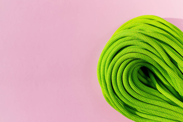 green rope for rock climbing and mountaineering lies on a colored background. background image of rope for active sports. sports equipment. - Fotografie, Obrázek