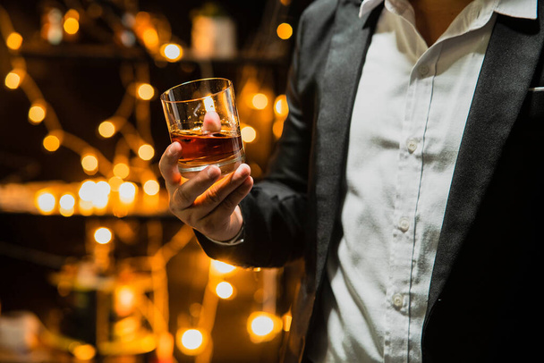 Επιχειρηματίας κάθεται κρατώντας ένα ποτήρι ουίσκι ποτό ουίσκι στην αίθουσα κάβα - Φωτογραφία, εικόνα