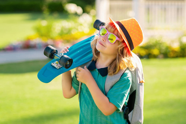 Summer kids fashion. Kid with skateboard. Child hold skate board. Healthy sport and activity for school kids in summer. Sports fun - Photo, image