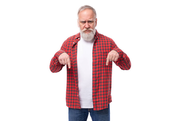 60歳の灰色の髪の年金受給者,ひげと口ひげが彼の指を横に示しています. - 写真・画像