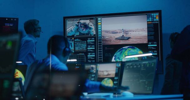 Оператори польоту контролюють космічну місію на комп'ютерах в командному центрі, спілкуються з астронавтом. Команда дивиться успішний запуск космічної ракети на великому цифровому екрані. Дослідження космосу
. - Фото, зображення