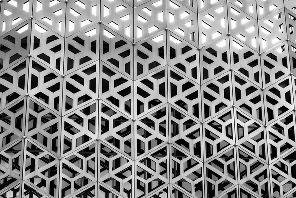 De textuur van de bekleding van een gebouw gemaakt van metalen aluminium panelen met een gesneden patroon. Abstracte achtergrond voor ontwerp. Zwart-wit. - Foto, afbeelding