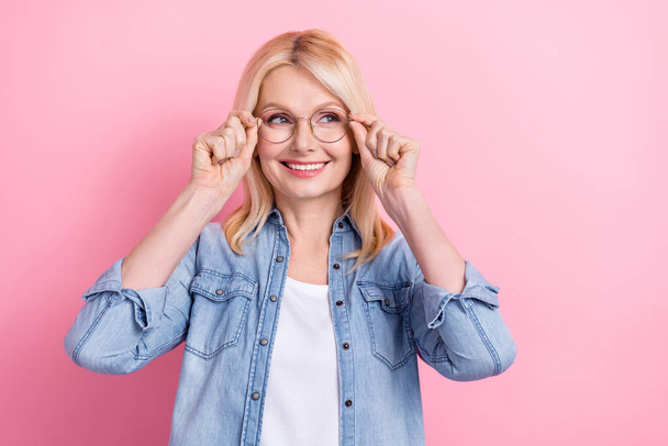 Photo of senior funny lady presenting computer glasses optician consultation reading side news isolated pink color background. - Фото, изображение