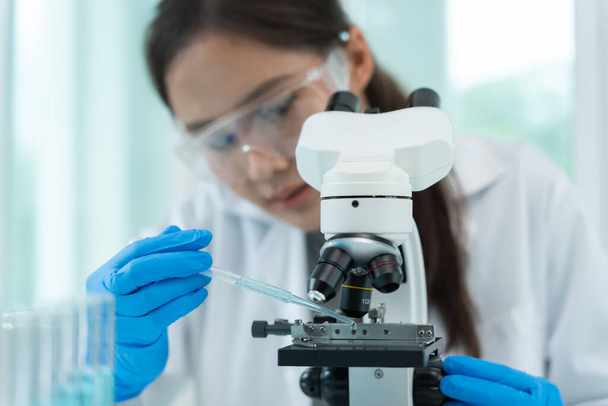 科学者は最先端の科学研究室で生化学試料を分析する。医療用顕微鏡はウイルスの微生物学的発達に見える。科学研究所のバイオテクノロジー研究 - 写真・画像