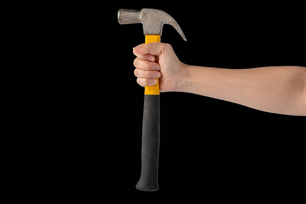 Hand with hammer on black background. - Фото, изображение