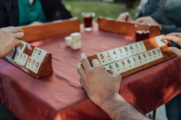 A group of men drink traditional Turkish tea and play a Turkish game called Okey.  - Zdjęcie, obraz