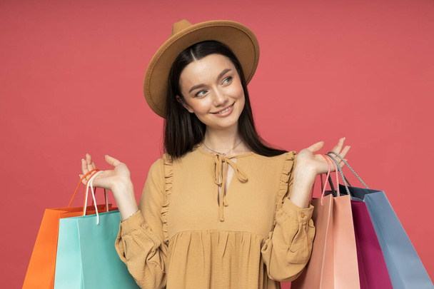 Mujer joven con bolsas de compras, sobre fondo rosa - Foto, imagen