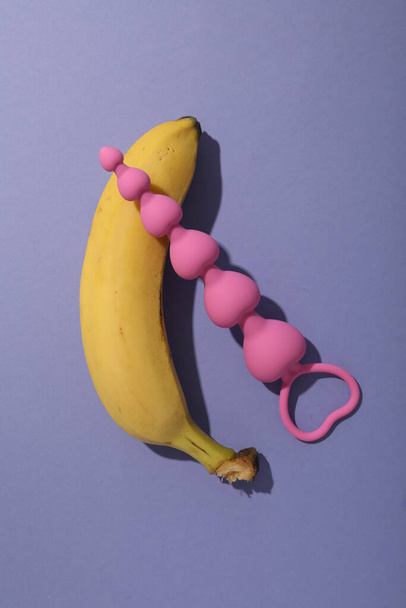 Banana with anal chain on purple background - Foto, Imagem