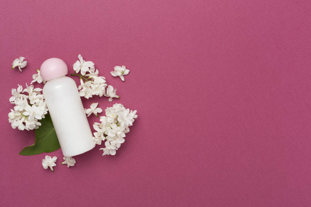 Zusammensetzung mit Kosmetikflasche und Blumen auf farbigem Hintergrund, Draufsicht - Foto, Bild