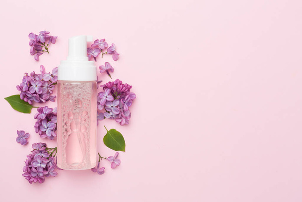Foaming facial cleanser and with flowers on color background, top view - Фото, зображення