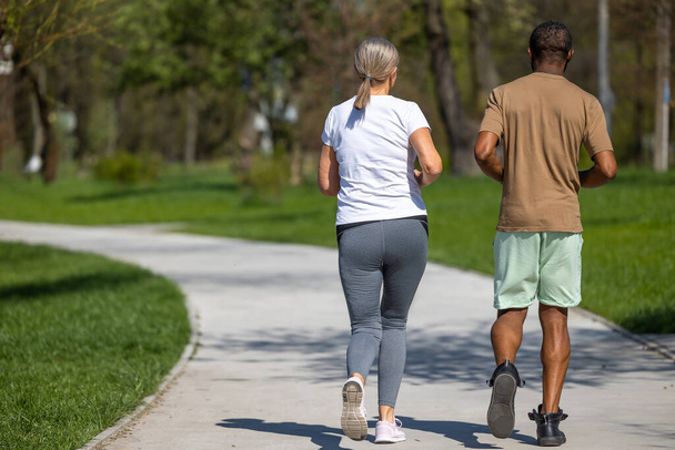 Jogging. Mature couple jogging in the park together - Фото, изображение