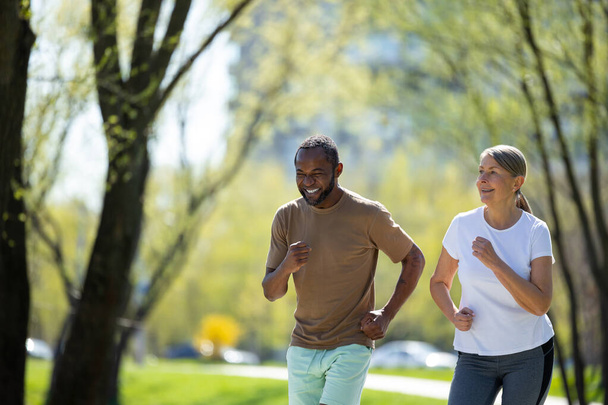 Healthy lifestyle. Mature couple jogging in the park in the morning - Photo, image