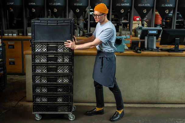 Adulto barista caucasiano aceita novo lote de café desempacotando caixas com mercadorias, preparando-se para o processo de trabalho no café. - Foto, Imagem