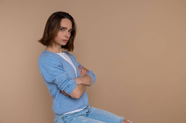 Offended sad unhappy woman in casual clothing looking at camera with folded hands isolated over beige background. - Foto, immagini