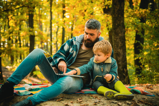 Parent teach baby. Happy Father and son with spending time outdoor in the autumn park. Both dad and child are laughing - Фото, зображення