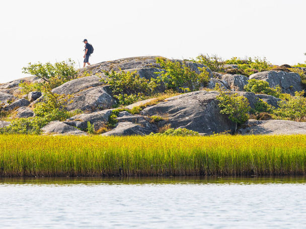 Aussichtsreiche Aufnahme eines männlichen Wanderers, der am felsigen Ufer spaziert - Foto, Bild