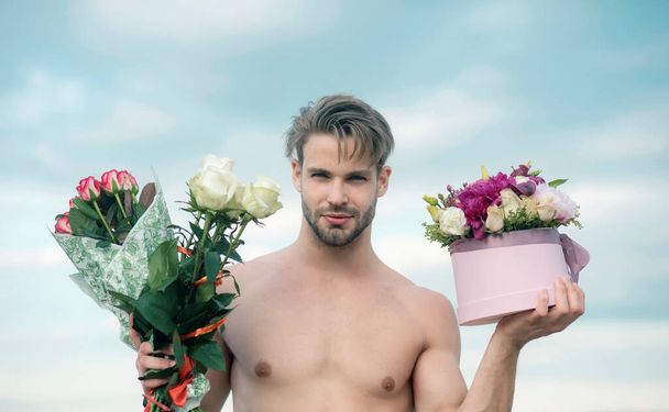 Sexy gift for beautiful woman. 8 march and womans day. A man is giving a beautiful bouquet and gift box to woman. Sexy closeup portrait of handsome topless male model with beautiful eyes on the sky - Фото, зображення