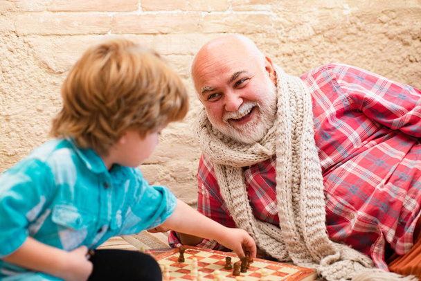 Mature man with little boy playing chess. Chess competition. Senior man thinking about his next move in a game of chess. Little boy playing chess with his Grandfather - Foto, Imagem