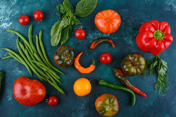 Verschiedene Sorten Tomaten, Paprika und Basilikum auf grünem Hintergrund - Foto, Bild