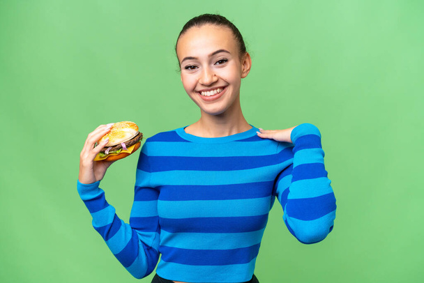 Junge Araberin hält lachend einen Burger in der Hand - Foto, Bild