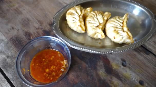 Fried momos or dumplings served with red hot chutney. Cinematic wooden table top shot. - Footage, Video