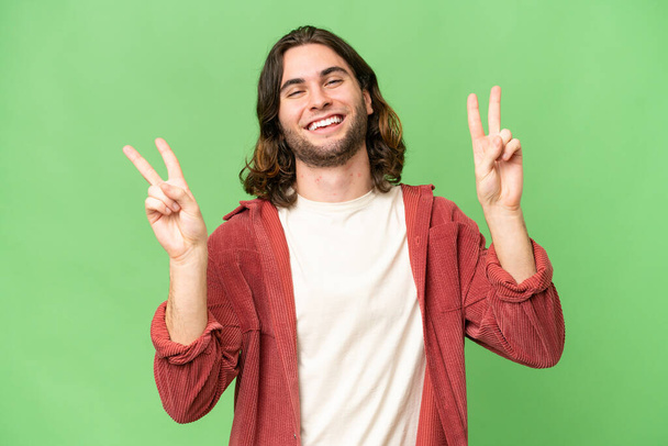 Junger gutaussehender Mann mit isoliertem Hintergrund zeigt mit beiden Händen Siegeszeichen - Foto, Bild