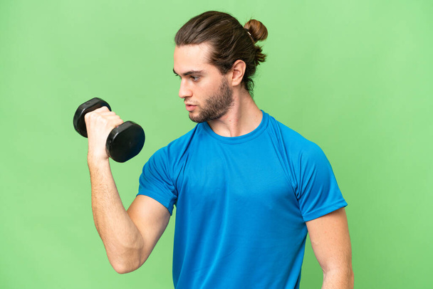 Young handsome man isolated on green chroma background making weightlifting - Fotó, kép