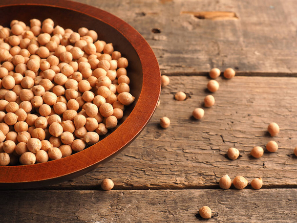 Organic dried chickpeas in a wooden bowl on a rustic wooden kitchen table, vegetarian protein, healthy food - 写真・画像