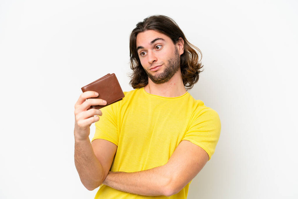 Fiatal jóképű férfi kezében egy pénztárca elszigetelt fehér háttér szomorú kifejezés - Fotó, kép