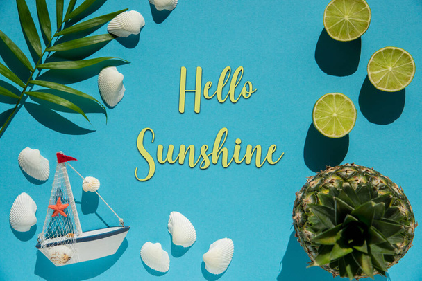 Flat Lay With English Text Hello Sunshine. Turquoise Or Blue Background Wit Decoration Like Pineapple, Shells, Boat And Lemons. - Photo, Image
