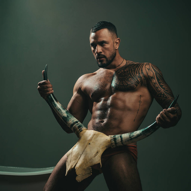 Sexy man with erotic masculine, body six pack hold bull horns. Sexy male torso, seductive stranger with muscular body. Guy hunk, brutal sex symbol - Фото, изображение