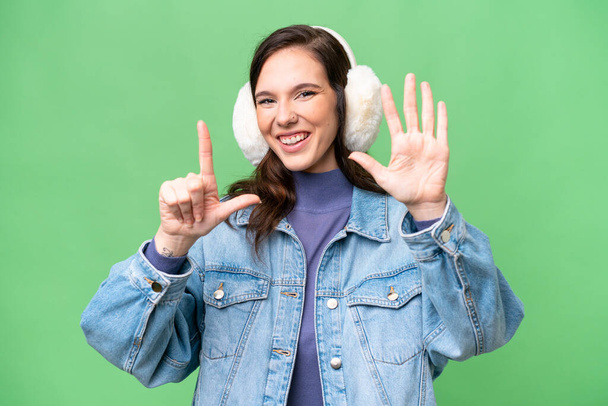 Young caucasian woman wearing winter muffs over isolated background counting seven with fingers - Foto, afbeelding