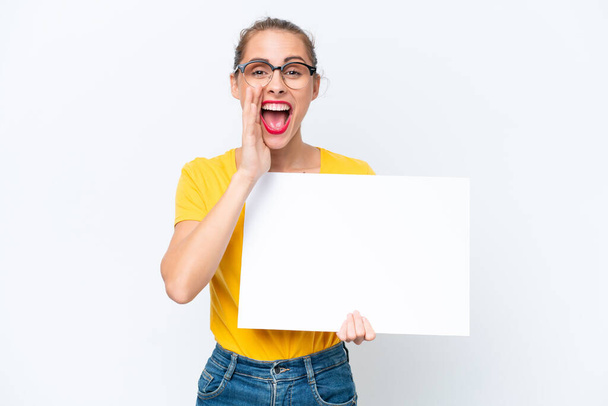 Young caucasian woman isolated on white background holding an empty placard and shouting - Photo, Image