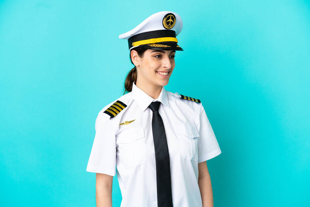 Repülőgép pilóta kaukázusi nő elszigetelt kék háttér látszó oldalán - Fotó, kép