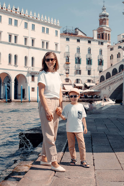 Egy erős és gyönyörű nő kecsesen sétál át Olaszországon, Velencén, a drágalátos kicsijével. - Fotó, kép