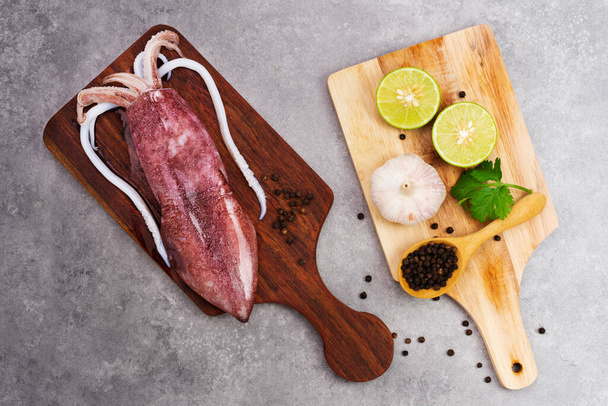 Fresh raw octopus on wooden chopping board background Seafood squid with lemon top view and copy space for your text - Fotó, kép