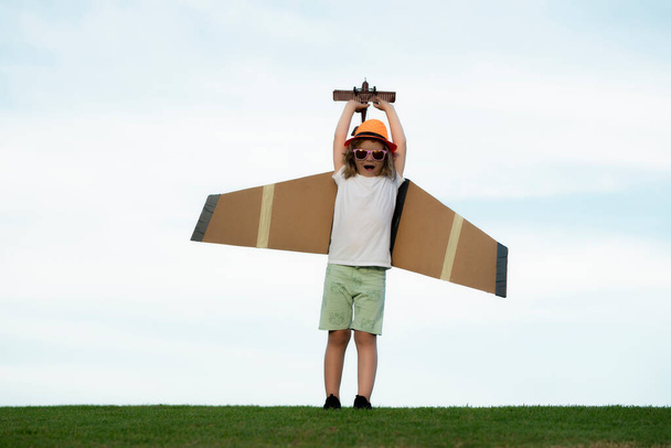 Kinderflieger mit Papierflügeln oder Spielzeugflugzeug träumt davon, im Sommer in der Natur zu reisen - Foto, Bild