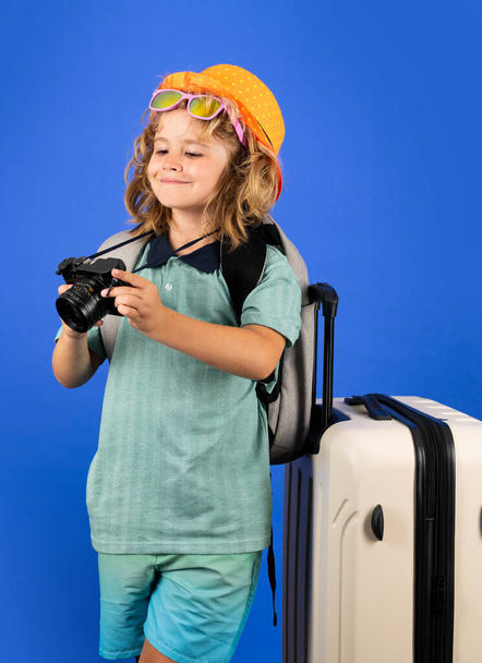 Traveler tourist kid boy 7-8 years old on isolated studio background. Travel on weekends getaway. Independent kid boy with big travel bag - Photo, Image