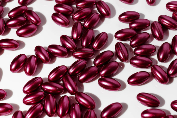 Muitas pílulas vermelhas no fundo branco. Preparações para o tratamento de resfriados, vitaminas, complexo de bem-estar - Foto, Imagem