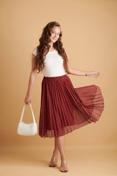 Полнометражный портрет веселой молодой женщины, одетой в длинную горошек юбку в летний день - Фото, изображение