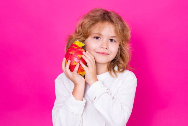 Healthy fruits for kids. Kid hold dragon fruit in studio. Studio portrait of cute child with dragon fruit isolated on pink background, copy space - Fotoğraf, Görsel