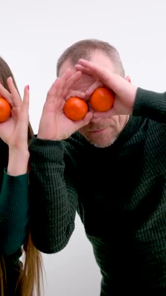 man and girl fooling around balding man and long-haired daughter joking playing troll each other tangerines holding tangerines near eyes for sale fresh  - Footage, Video