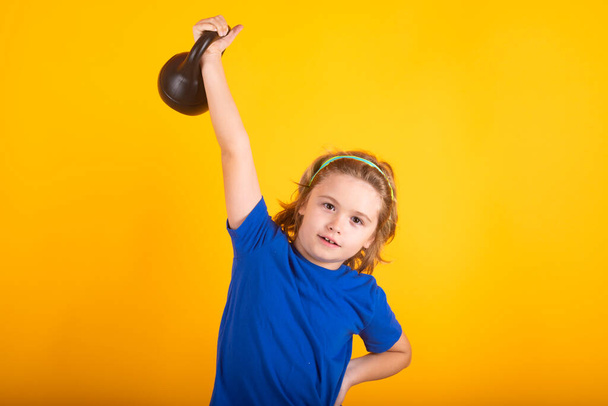 Sporty kids, studio isolated portrait on yellow background. Kids sports exercises. Healthy kids life and sport concept. Portrait of child boy working out with dumbbells - Photo, Image