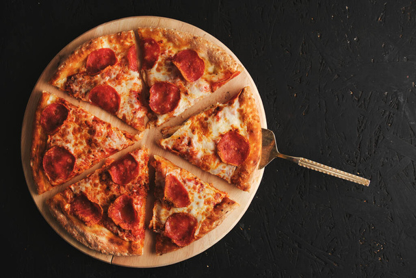 Pepperoni pizza with sausage dark background - Foto, afbeelding